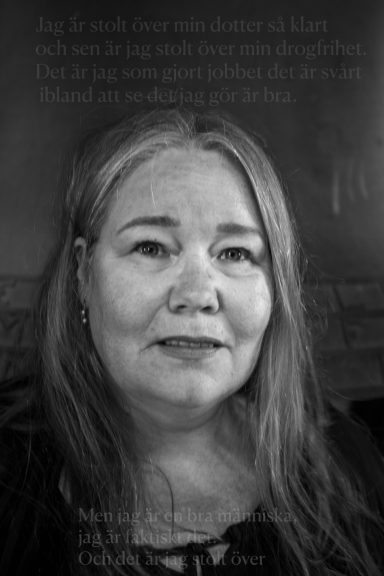 Porträtt av en kvinna med långt, grått hår som ser rakt in i kameran.